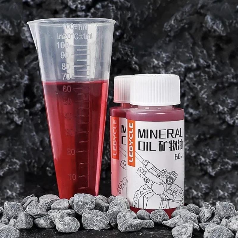 Huile minérale rouge versée dans une éprouvette graduée, montrant les 60 ml du flacon