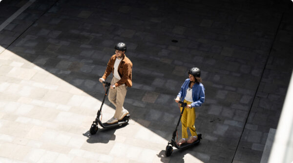 Deux personnes circulent en ville sur des trottinettes électriques Ninebot E2