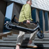 Trottinette électrique Ninebot E2 E II pliée et portée à la main dans un escalier