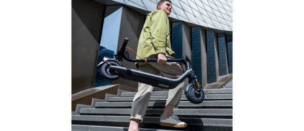 Trottinette électrique Ninebot E2 E II pliée et portée à la main dans un escalier