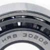 Gros plan sur la cage du cône avec le marquage 30202 gravé entre les rouleaux Gros plan sur la cage du cône avec le marquage 30202 gravé entre les rouleaux