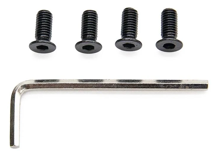 Les quatre vis noires alignées, empreintes six pans creux vers l'objectif, et la clé six pans posée en dessous.